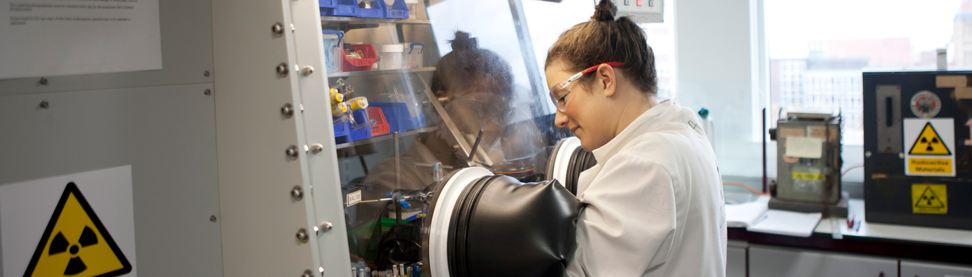 Researcher smiling with hands in radioactive material machine